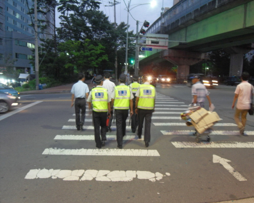 정사복 경찰들이 야간 순찰 활동을 펼치고 있는 가운데 횡단보도에서 모두 좌측보행을 하고 있다.