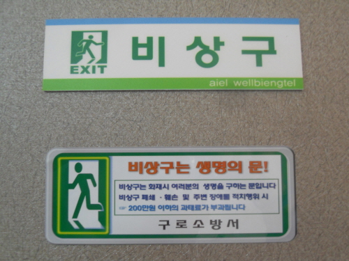 한 건물 벽에 부착된 ‘비상구’안내판과 소방서에서 캠페인용으로 부착한 스티커 ‘비상구는 생명의 문!’문구가 선명하다.