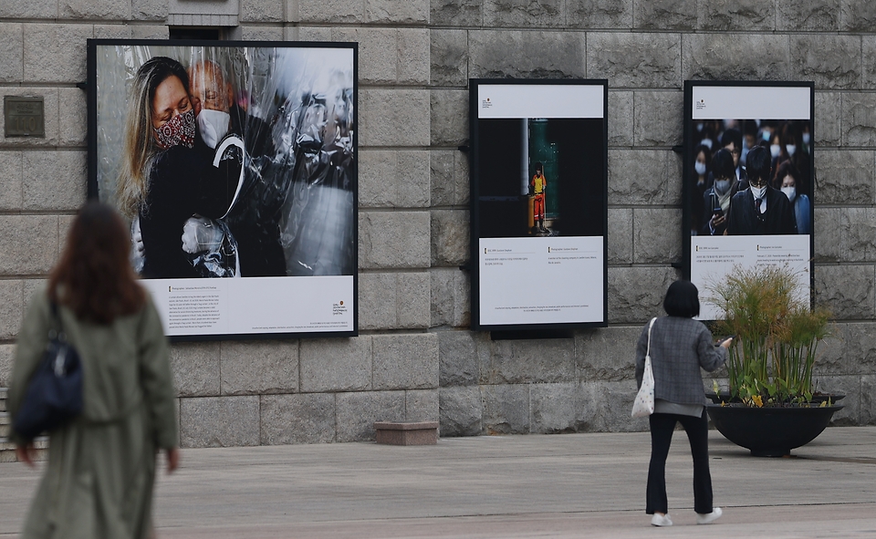 서울 중구 서울도서관 외벽에 서울시와 함께하는 2020 서울글로벌포토저널리즘 사진전이 설치되어 출근하는 시민들이 지나가며 보고 있다. 