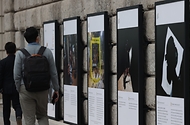 서울 중구 서울도서관 외벽에 서울시와 함께하는 2020 서울글로벌포토저널리즘 사진전이 설치되어 출근하는 시민들이 지나가며 보고 있다. 