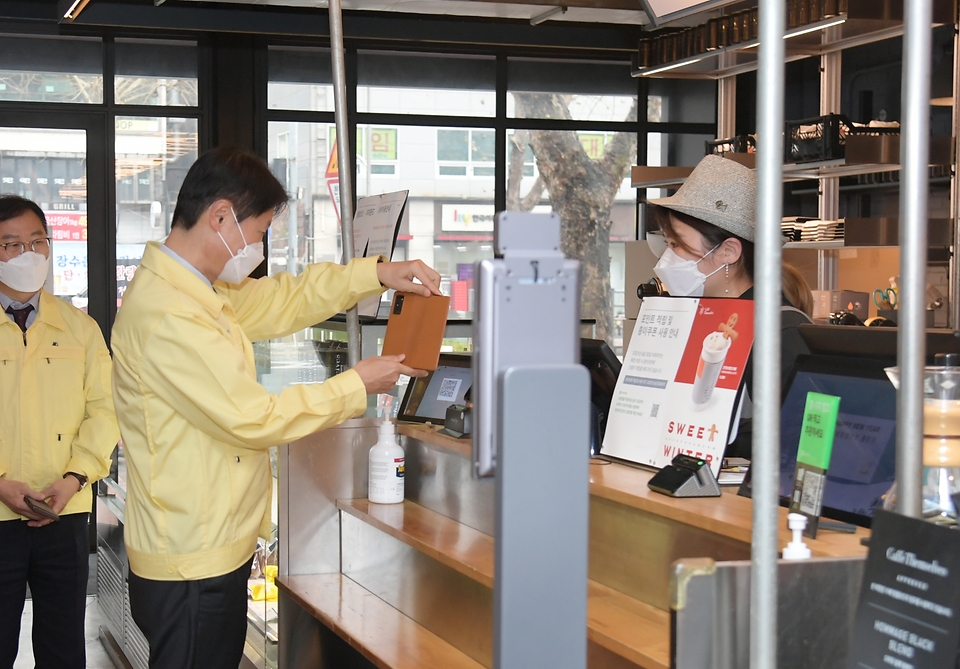 김강립 식품의약품안전처장이 22일 서울 종로구의 한 카페를 방문해 QR코드로 전자출입명부를 작성하고 있다.