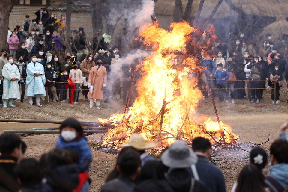 28일 봄이 찾아온 듯 포근한 오후 경기도 용인시 한국민속촌에서 보름이 바로 지난 일요일, 민속촌을 방문한 관람객들이 참석한 가운데 정월대보름 달집태우기를 하고 있다. 정월대보름에 생솔가지와 나뭇더미를 쌓아 ‘달집’을 짓고, 달이 떠오르면 불을 놓아 한 해의 액운을 막고 복을 기원했다고 한다.