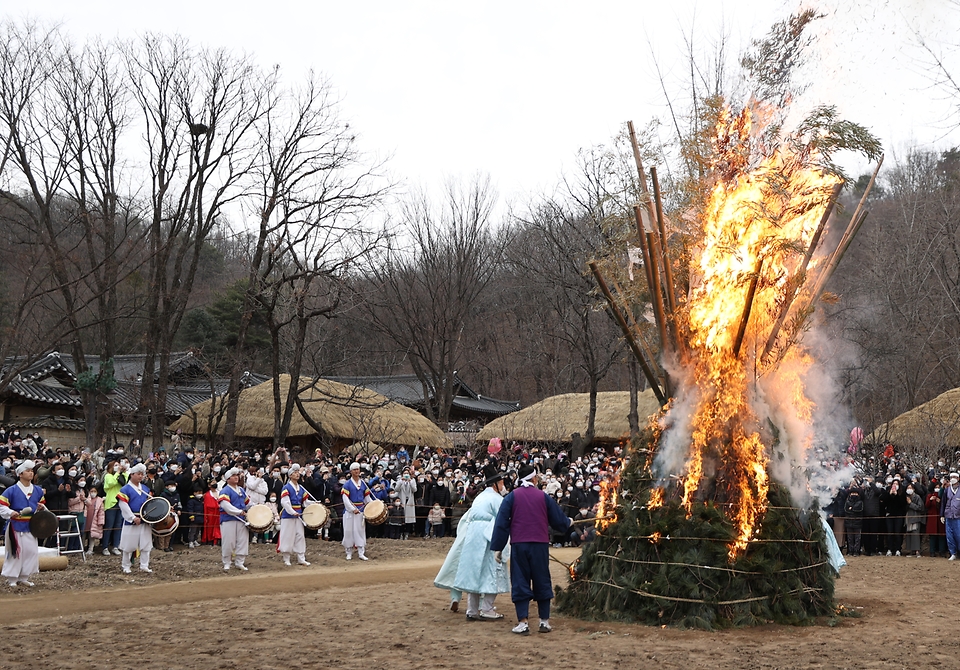 28일 봄이 찾아온 듯 포근한 오후 경기도 용인시 한국민속촌에서 보름이 바로 지난 일요일, 민속촌을 방문한 관람객들이 참석한 가운데 정월대보름 달집태우기를 하고 있다. 정월대보름에 생솔가지와 나뭇더미를 쌓아 ‘달집’을 짓고, 달이 떠오르면 불을 놓아 한 해의 액운을 막고 복을 기원했다고 한다.