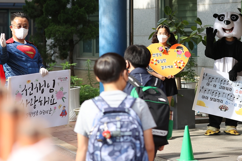 스승의 날을 하루 앞두고 서울 동작구 보라매초등학교 학생들이 교장 선생님과 함께 출근하는 선생님들에게 감사의 마음을 담은 팻말을 들어 보이며 인사하고 있다.