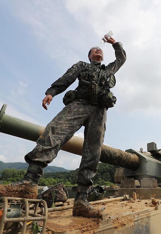 3일 경기도 포천시 꽃봉훈련장에서 실시된 K9A1 자주포 사격훈련 종료 후 한 장병이 폭염에 대비한 온열손상키트에 포함된 생수를 머리에 부으며 더위를 식히고 있다. (출처=국방일보)