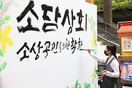 15일 서울 인사동 쌈지길에서 열린 소상공인 플래그십 스토어 개장행사에서 명인의 대형 붓글씨 연출을 통해 코로나19로 지친 소상공인을 위로하고 있다.