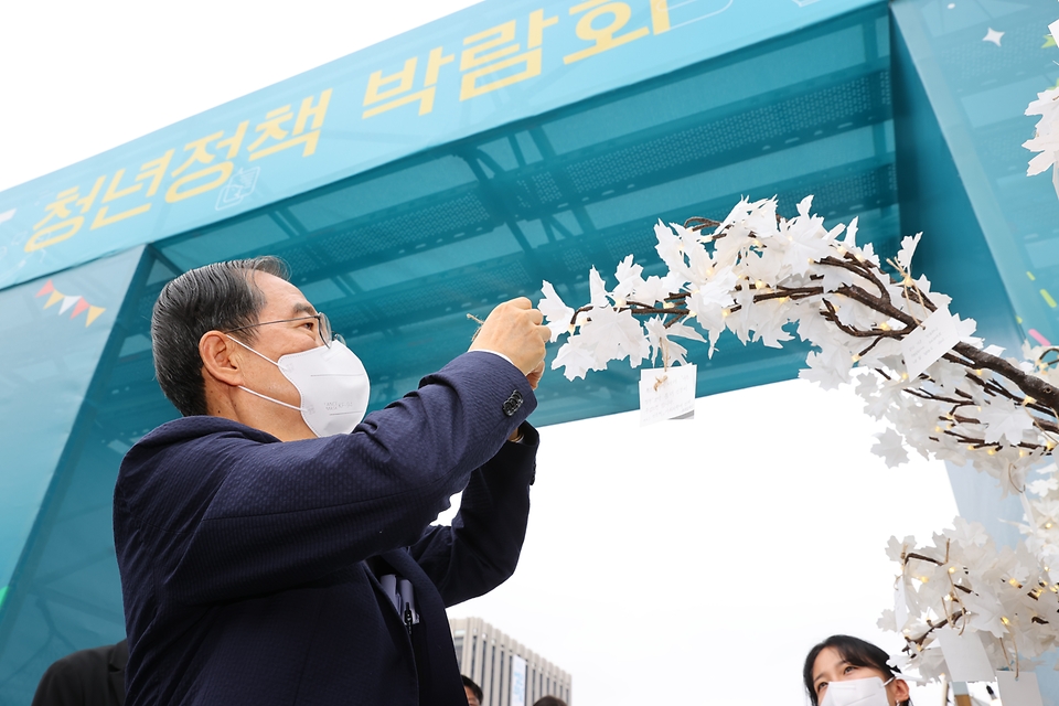 한덕수 국무총리가 17일 서울 종로구 광화문광장에서 열린 2022 청년의 날 기념식에 참석해 소원나무에 메모를 남기고 있다.