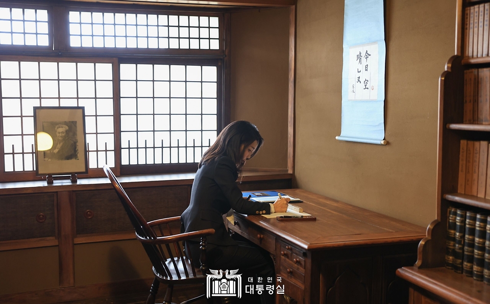 김건희 여사가 17일 일본 도쿄 민예관에서 설립자인 야나기 무네요시가 생전 사용했던 책상에 앉아 방명록을 작성하고 있다.