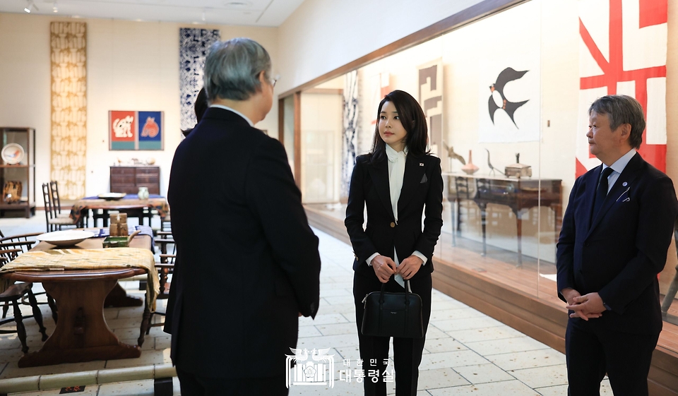 김건희 여사가 17일 일본 도쿄 민예관에서 공예품에 관한 관계자의 설명을 듣고 있다.