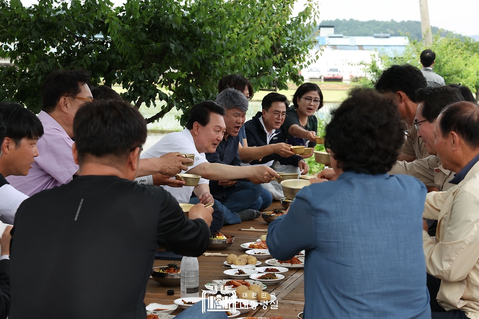 윤석열 대통령이 7일 충남 부여군 꿈에영농조합법인을 방문해 모내기를 마친 뒤 주민들과 새참을 먹고 있다.