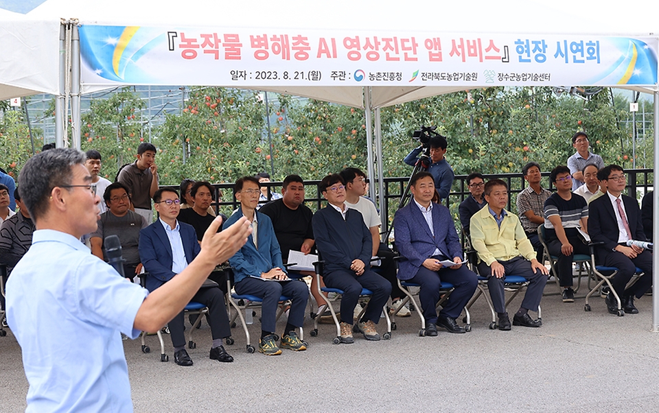 조재호 농촌진흥청장이 21일 전북 장수군 농업기술센터 사과 전시재배지에서 열린 ‘농작물 병해충 인공지능 영상진단·처방 앱 서비스 현장 시연회’에 참석해 관계자로부터 설명을 듣고 있다.