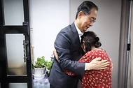 한덕수 국무총리가 26일 서울 성동구 주택가를 찾아 홀로 살고 있는 박인애 씨에게 우유를 배달한 뒤 격려하고 있다.