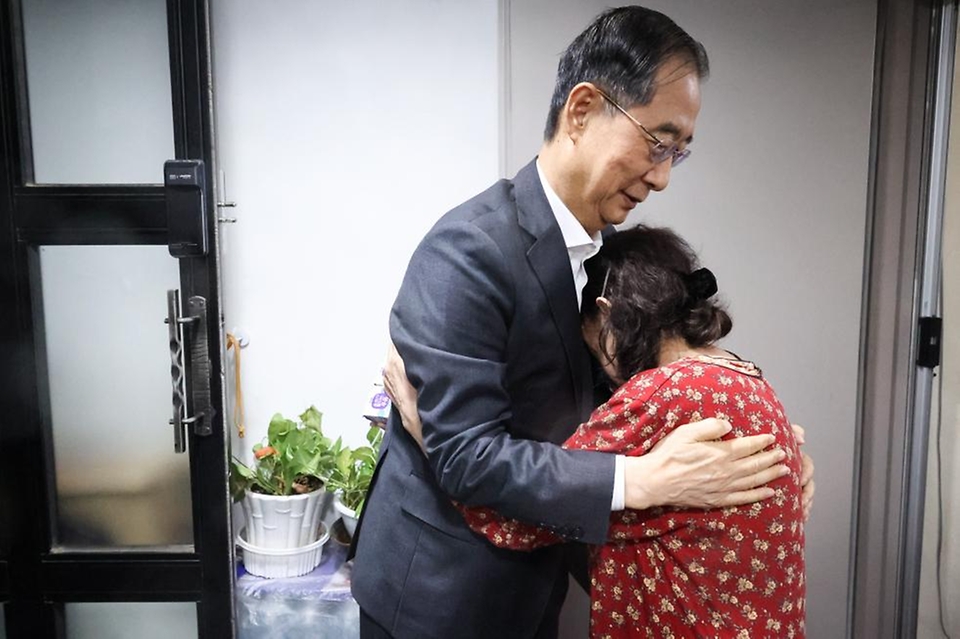 한덕수 국무총리가 26일 서울 성동구 주택가를 찾아 홀로 살고 있는 박인애 씨에게 우유를 배달한 뒤 격려하고 있다.