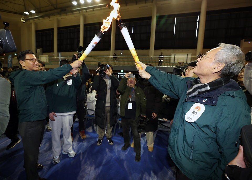유인촌 문화체육관광부 장관이 28일 강원도 원주 육민관고 체육관에서 열린 ‘2024강원동계청소년올림픽 원주 성화투어 행사’에 참석해 김재열 IOC 위원에게 성화를 인계 받고 있다.