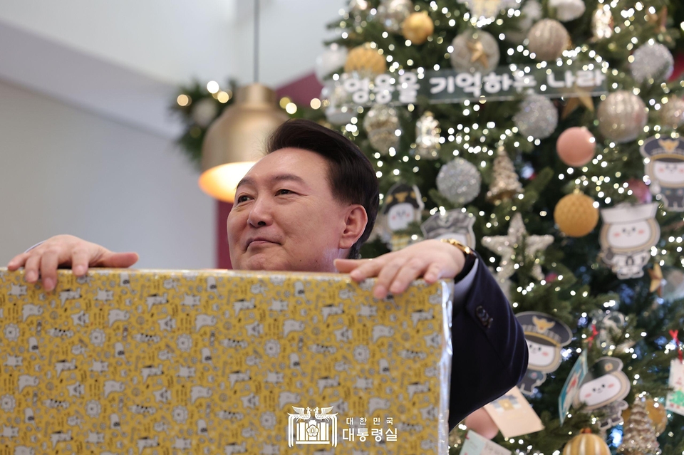 윤석열 대통령이 22일 서울 용산 대통령실 청사에서 열린 ‘히어로즈 패밀리와 함께하는 꿈과 희망의 크리스마스 행사’에서 어린이들에게 줄 선물을 들고 있다.