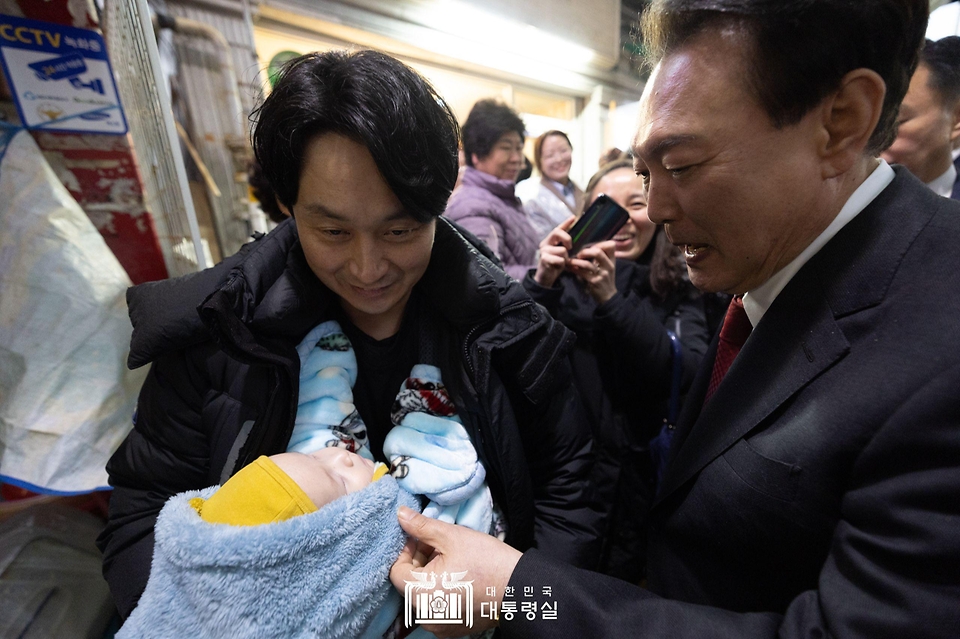 윤석열 대통령이 21일 울산 남구 신정상가시장을 방문해 만난 아기를 보고 있다.