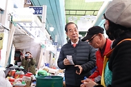 한덕수 국무총리가 21일 충남 공주시 공주산성시장에서 물건을 구입하며 소상공인들과 이야기를 나누고 있다.