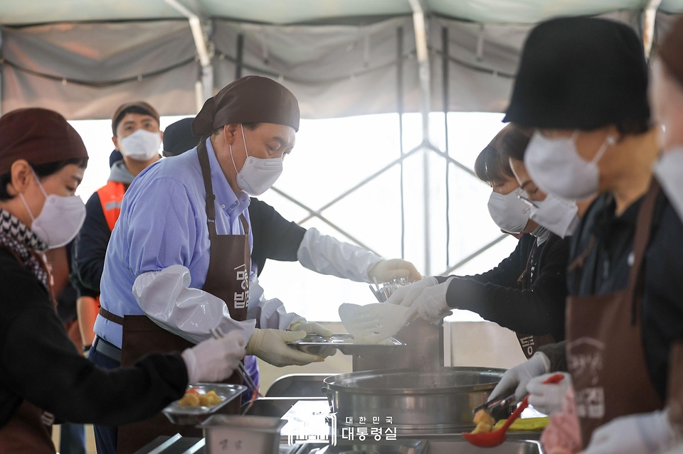 윤석열 대통령이 27일 서울 명동성당 내 무료 급식소인 ‘명동밥집’에서 봉사활동을 펼치며 급식장 내 빈 테이블에 놓을 식판에 배식을 받고 있다.