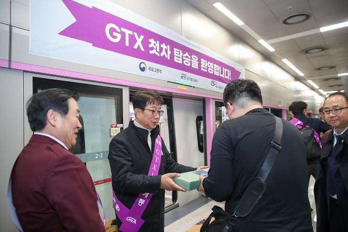 박상우 국토교통부 장관이 30일 경기 화성시 동탄역에서 GTX-A 첫 열차의 탑승객을 맞이하며 기념품을 전해주고 있다.
