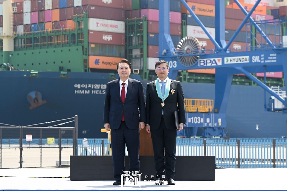 윤석열 대통령이 5일 경남 창원시 진해구 부산항 신항 7부두 개장식에서 김남정 동원그룹 회장에게 은탑산업훈장을 친수한 뒤 기념 촬영을 하고 있다. 