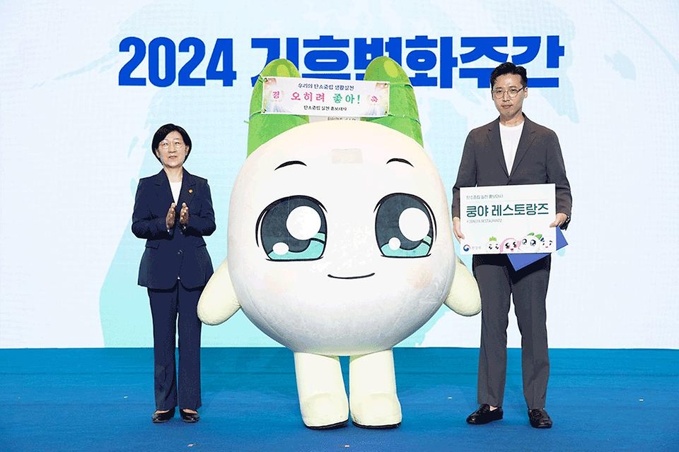 한화진 환경부 장관이 22일 서울 강남구 코엑스에서 열린 ‘2024 기후변화주간’ 개막식에서 넷마블 쿵야레스토랑즈 캐릭터 ‘쿵야’에게 탄소중립 실천 홍보대사 위촉장을 수여한 후 배민호 넷마블 MNB 대표이사와 함께 기념 촬영을 하고 있다.