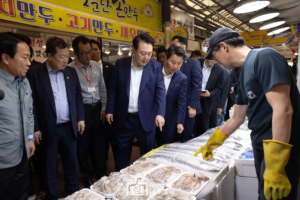윤석열 대통령이 10일 서울 서대문구 영천시장을 찾아 한 점포에서 수산물을 살피고 있다. 