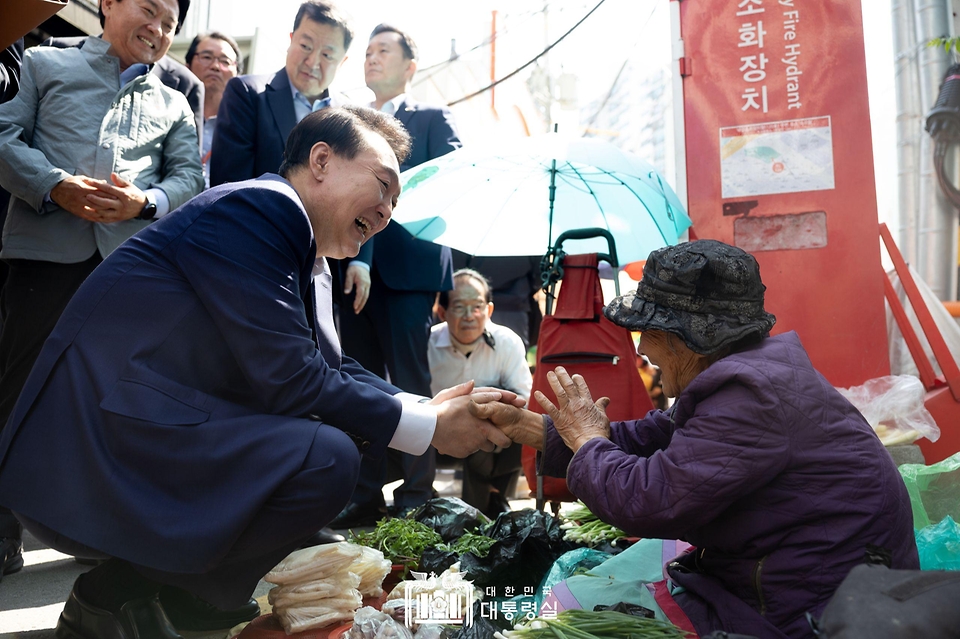 윤석열 대통령이 10일 서울 서대문구 영천시장을 찾아 노점에서 채소를 판매하는 어르신과 인사하고 있다. 