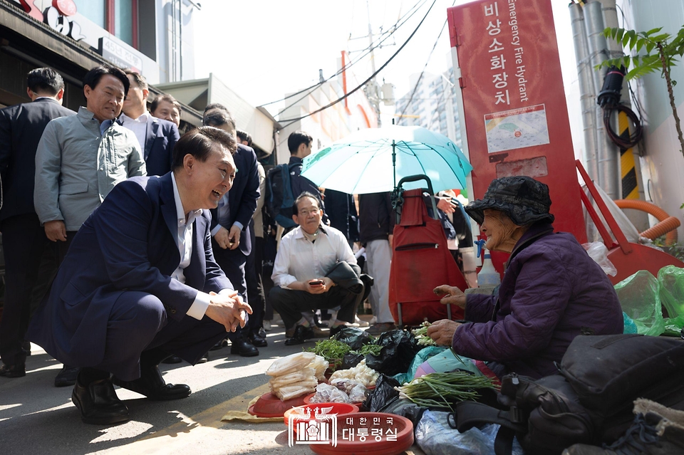 윤석열 대통령이 10일 서울 서대문구 영천시장을 찾아 노점에서 채소를 판매하는 어르신과 대화하고 있다.