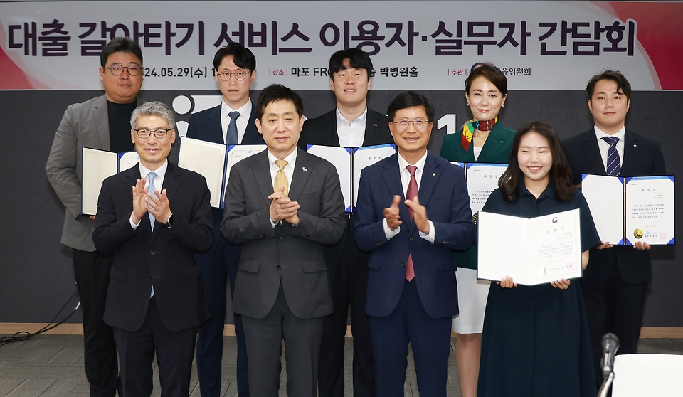 김주현 금융위원회 위원장이 29일 오전 서울 마포구 마포 프론트원에서 개최한 대출 갈아타기 서비스 간담회에서 대출 갈아타기 서비스 운영에 기여한 금융권 및 대출비교플랫폼 등 직원에 대해 포상을 수여하고, 참석자들과 기념촬영을 하고 있다.

(앞줄 왼쪽부터 시계 반대방향으로) 이준수 금융감독원 부원장, 김주현 금융위원회 위원장, 박종석 금융결제원 원장, 권수현 금융결제원 계장, 오인식 우리은행 대리, 송유정 하나은행 차장, 조현우 국민은행 대리, 이무용 신한은행 과장, 김태경 네이버페이 리더.