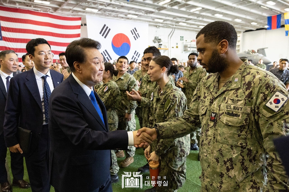 윤석열 대통령이 25일 부산 해군작전기지에서 미 해군 항공모함 시어도어 루즈벨트함에 승선해 발언 뒤 한미 장병들과 인사하며 이동하고 있다. 