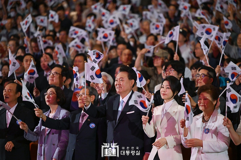 윤석열 대통령과 김건희 여사가 15일 서울 종로구 세종문화회관에서 열린 ‘제79주년 광복절 경축식’에서 태극기를 흔들고 있다.