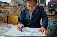 이재명 대통령이 13일 기본소득 실시지역 현황점검을 위해 방문한 경기도 연천군 식당에서 방명록을 남기고 있다.