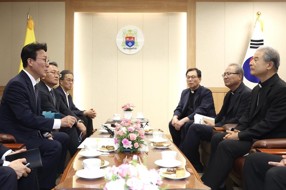 김민석 국무총리가 10일 경기 수원시 천주교수원교구청에서 한국천주교주교회의 의장인 이용훈 주교를 예방, 꽃다발을 들고 기념 촬영하고 있다.