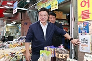 윤호중 행안부 장관이 24일 오후 서울 금천구 비단길 현대시장을 방문하여 민생회복 소비쿠폰 사용가능 매장 스티커를 부착하며 상인들을 격려하고 있다.