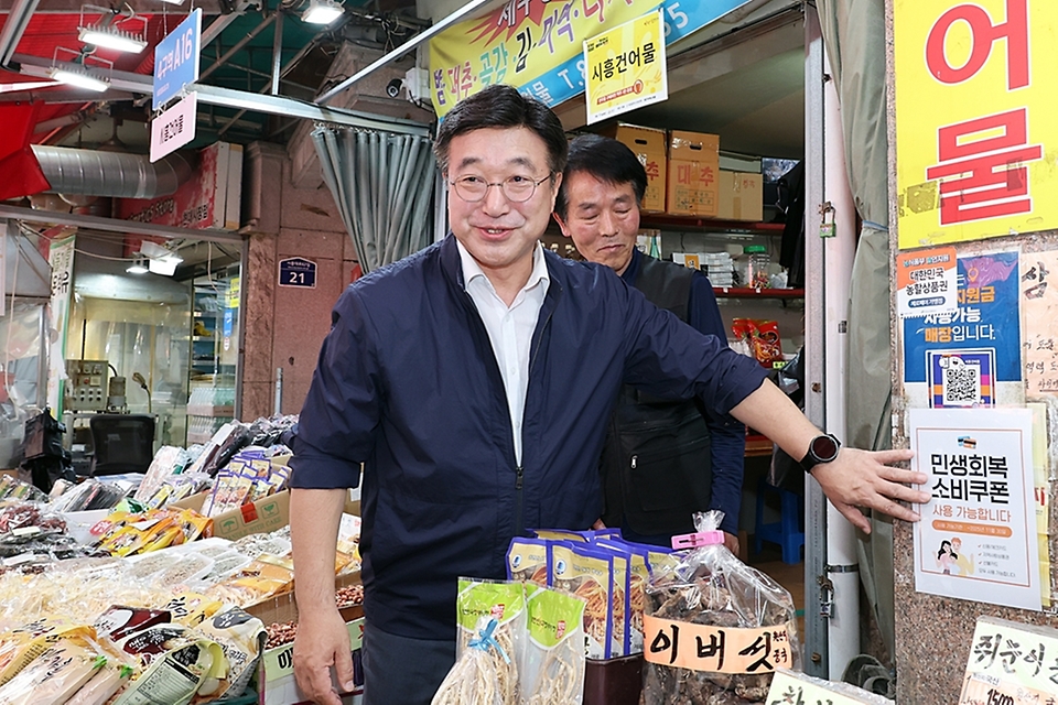 윤호중 행안부 장관이 24일 오후 서울 금천구 비단길 현대시장을 방문하여 민생회복 소비쿠폰 사용가능 매장 스티커를 부착하며 상인들을 격려하고 있다.