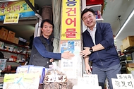 윤호중 행안부 장관이 24일 오후 서울 금천구 비단길 현대시장을 방문하여 민생회복 소비쿠폰 사용가능 매장 스티커를 부착하며 상인들을 격려하고 있다.