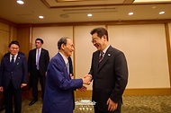 이재명 대통령이 24일 일본 도쿄의 한 호텔에서 일한의원연맹 회장인 스가 요시히데 전 일본 총리를 만나 인사하고 있다.