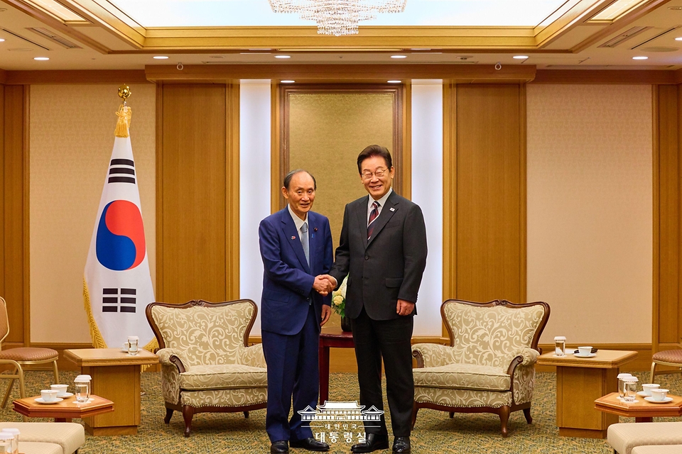 이재명 대통령이 24일 일본 도쿄의 한 호텔에서 일한의원연맹 회장인 스가 요시히데 전 일본 총리를 만나 인사하고 있다.