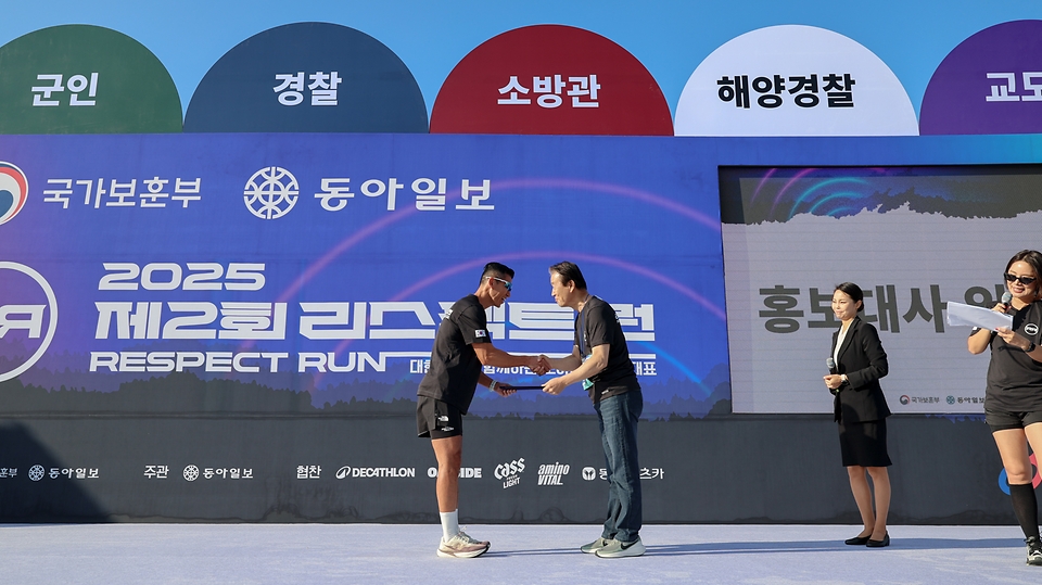 권오을 국가보훈부 장관이 27일 오전 경기도 하남시 미사경정공원에서 열린 제복근무자 감사마라톤 2025 제2회 리스팩트 런행사에 참석하여 가수 션에게 홍보대사 임명장을 전달 하고 있다.