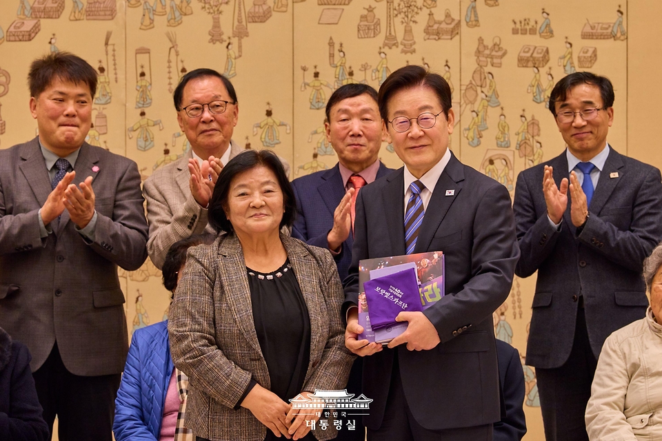 이재명 대통령이 13일 서울 용산 대통령실 청사에서 열린 민주화실천가족운동협의회 초청 오찬 간담회에서 조순덕 민가협 상임의장으로부터 민가협 40주년 기념 사진첩을 받고 있다. 