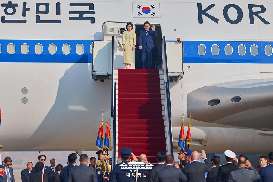 이집트 공식 방문 일정을 마친 이재명 대통령과 김혜경 여사가 21일(현지시간) 카이로 국제공항에서 남아프리카공화국 요하네스버그로 출발하기 위해 공군 1호기에 탑승해 인사하고 있다. 