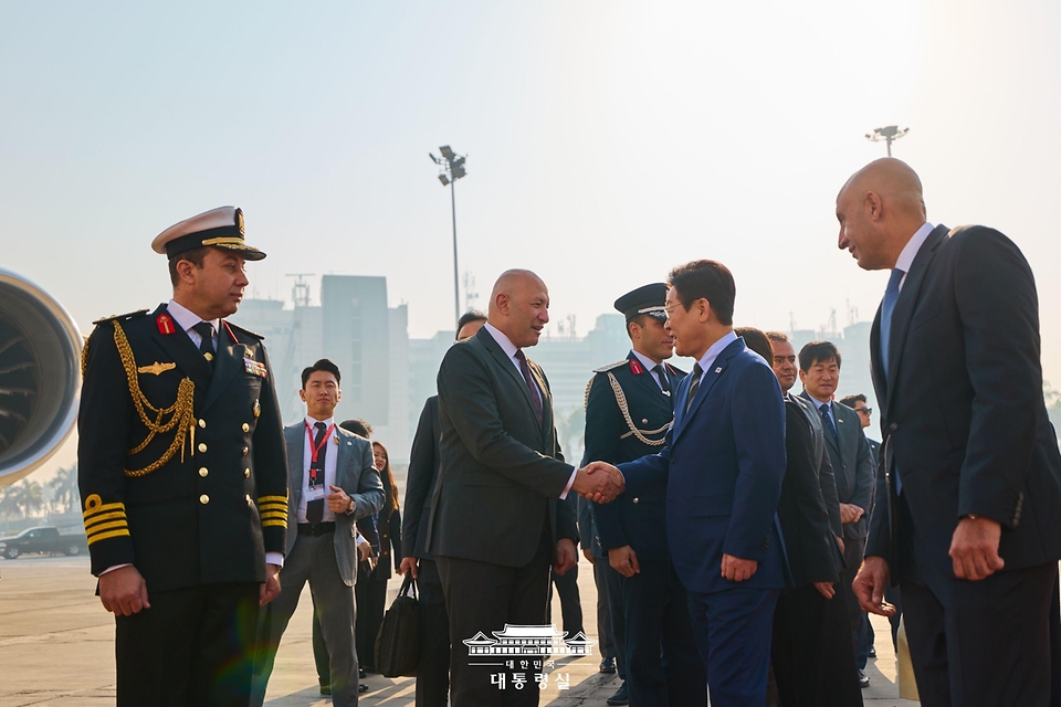 이집트 공식 방문 일정을 마친 이재명 대통령이 21일(현지시간) 카이로 국제공항에서 남아프리카공화국 요하네스버그로 출발하기 전 환송인사와 악수하고 있다. 