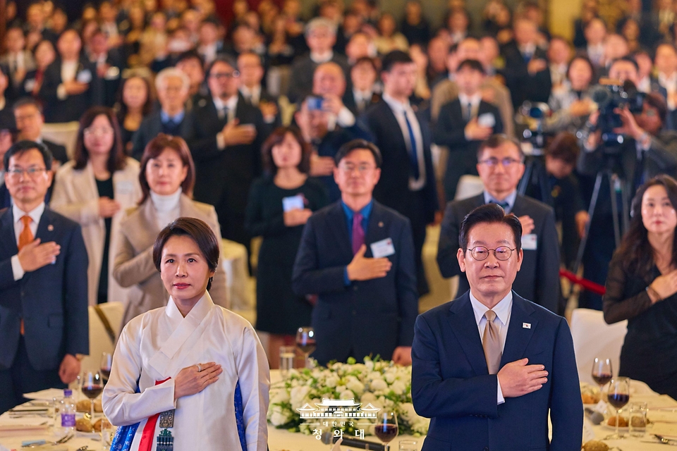 이재명 대통령과 김혜경 여사가 1월 4일 중국 베이징 한 호텔에서 열린 재중 한국인 간담회에서 국기에 경례하고 있다.