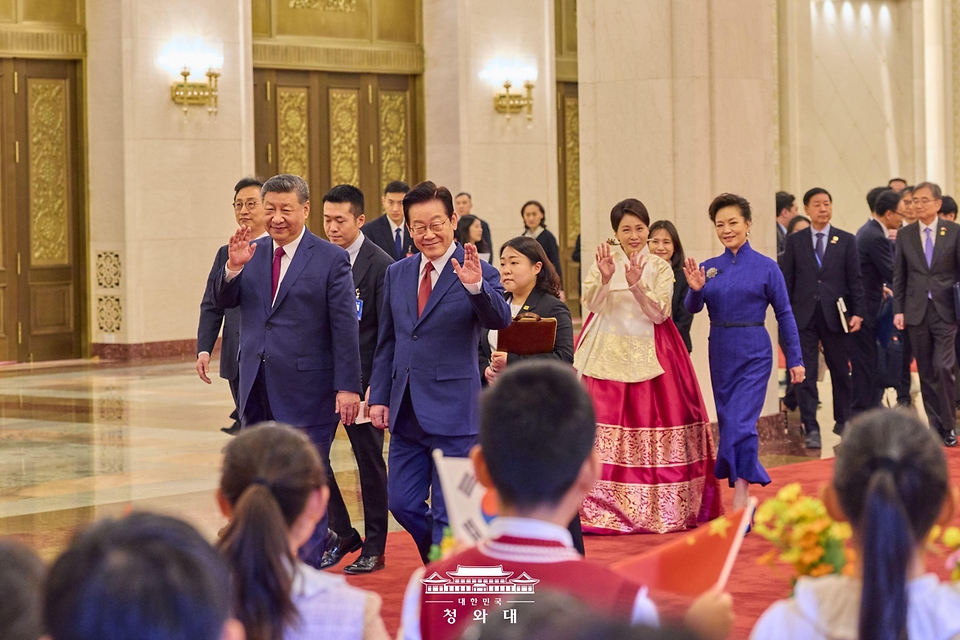 중국을 국빈 방문 중인 이재명 대통령과 김혜경 여사가 1월 5일(현지 시간) 중국 베이징 인민대회당에서 열린 공식환영식에서 시진핑 국가주석, 부인 펑리위안 여사와 이동하며 환영 나온 어린이들을 향해 손을 흔들고 있다. 