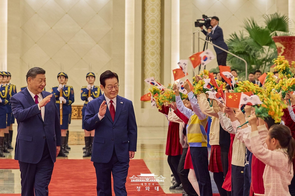 중국을 국빈 방문 중인 이재명 대통령이 1월 5일(현지 시간) 중국 베이징 인민대회당에서 열린 공식환영식에서 시진핑 국가주석과 이동하며 환영 나온 어린이들에게 인사하고 있다. 