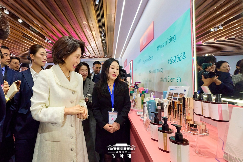 이재명 대통령과 중국을 방문 중인 김혜경 여사가 1월 7일(현지 시간) 중국 상하이 푸싱아트센터에서 열린 K-뷰티행사에서 한 부스 관계자의 설명을 듣고 있다.