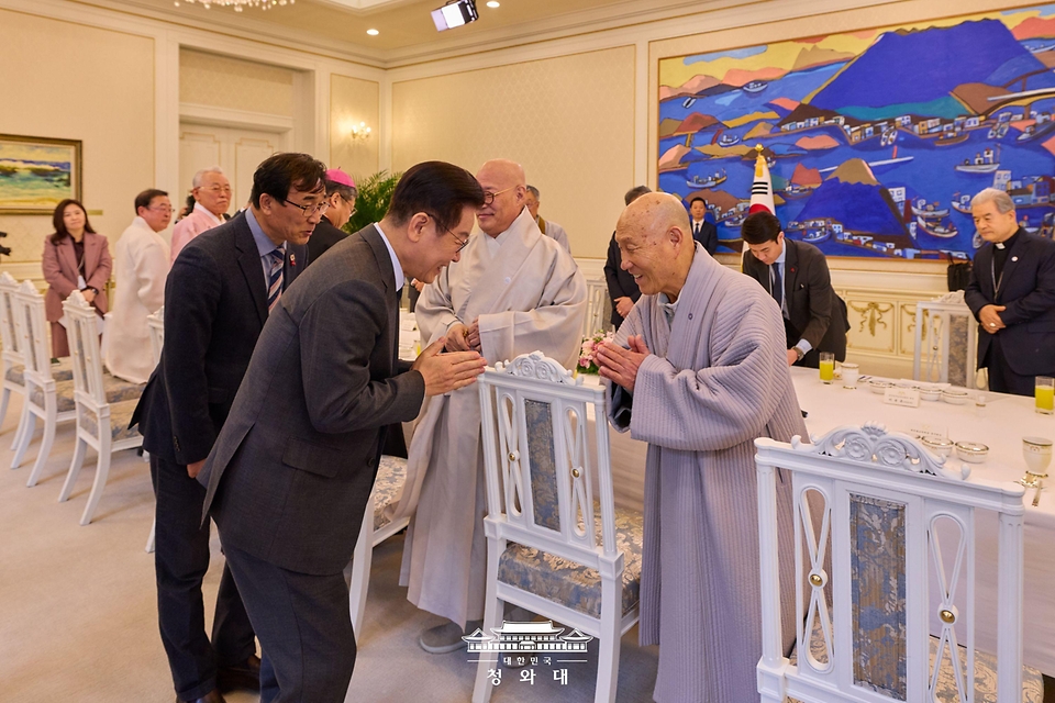이재명 대통령이 1월 12일 청와대 본관에서 열린 종교 지도자 초청 오찬간담회에서 대한불교천태종 총무원장 덕수스님과 인사하며 합장하고 있다.