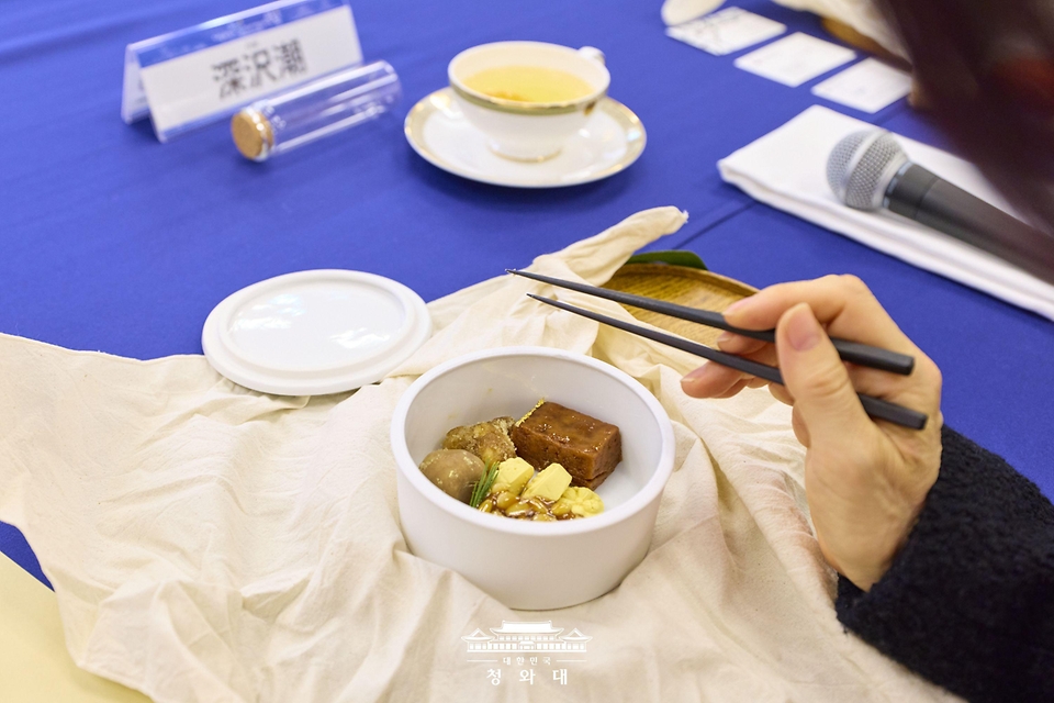 이재명 대통령과 함께 일본을 방문한 김혜경 여사가 1월 13일 일본 나라컨벤션센터에서 열린 재일 한국계 예술인 간담회에서 준비한 다과를 참석자가 맛보고 있다.