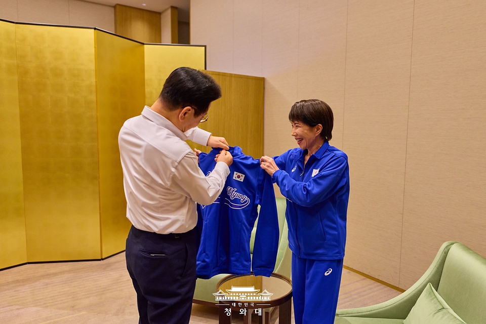 이재명 대통령이 1월 13일 일본 나라현 환담장에서 드럼 합주 전 다카이치 사나에 일본 총리가 준비한 옷을 받고 있다. 양 정상은 '케이팝 데몬 헌터스'의 주제가 '골든'과 BTS의 히트곡 '다이너마이트'에 맞춰 드럼을 함께 연주했다. 다카이치 총리는 학창 시절 헤비메탈 록밴드 드러머로 활동했다.