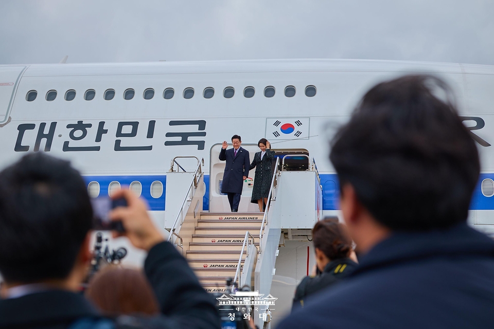 이재명 대통령과 김혜경 여사가 1월 13일 일본 오사카 간사이국제공항에 도착한 공군 1호기에서 환영객에게 인사하고 있다.